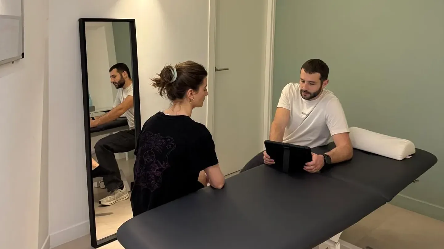 Une salle de soin du cabinet Kinactiv Sport : un kinésithérapeute et une patiente de part et d'autre d'une table de massage.